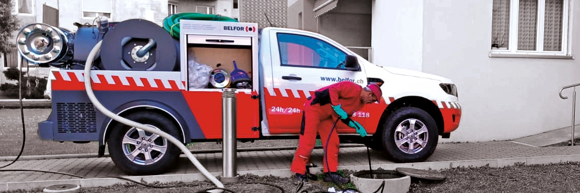 Un dipendente Belfor davanti al suo furgone da lavoro. Sta pulendo un tombino.