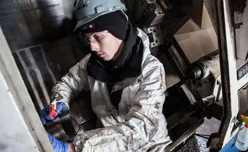 BELFOR technician cleans inside of production machinery